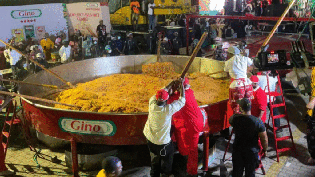 Chef Hilda Baci standing beside massive pot containing 8,780kg world record jollof rice serving in Lagos Nigeria