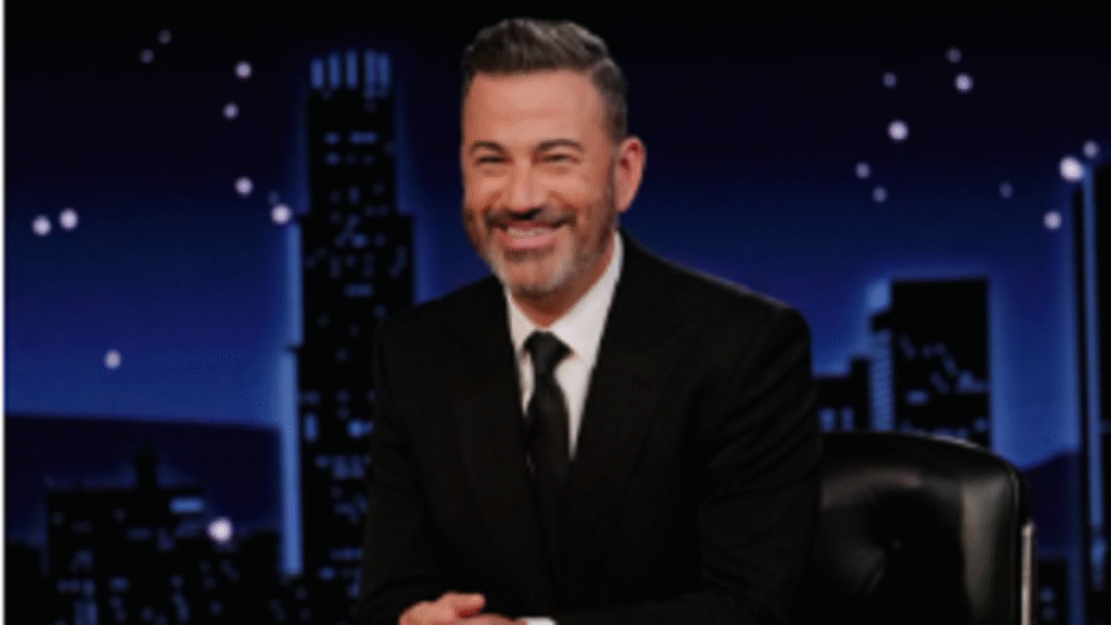 Jimmy Kimmel sitting at his late-night talk show desk with ABC studio lighting and backdrop visible