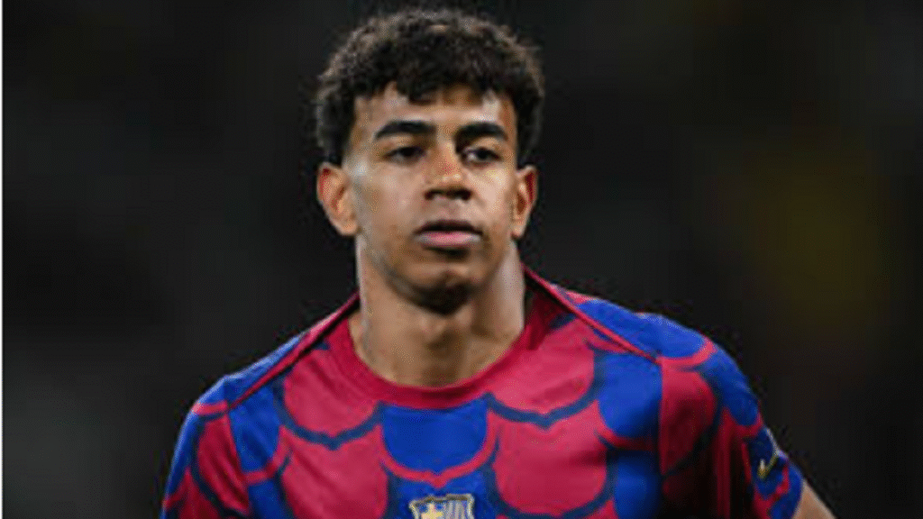 Lamine Yamal smiling while holding the golden Kopa Trophy award at the Ballon d'Or ceremony podium in Paris